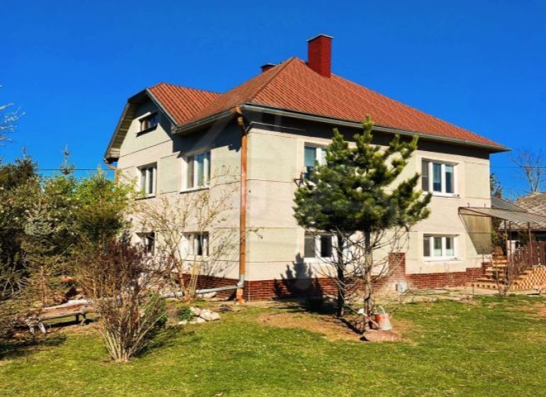 A family house in Nové Hony with a red roof, surrounded by a garden with coniferous trees.