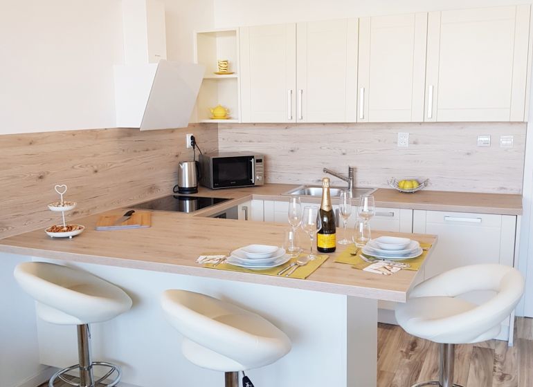 A kitchen with an island, bar stools, and a wood-patterned floor in a studio apartment.