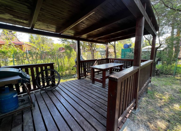A wooden gazebo in the Gardens in Lozorno with seating, surrounded by dense vegetation.