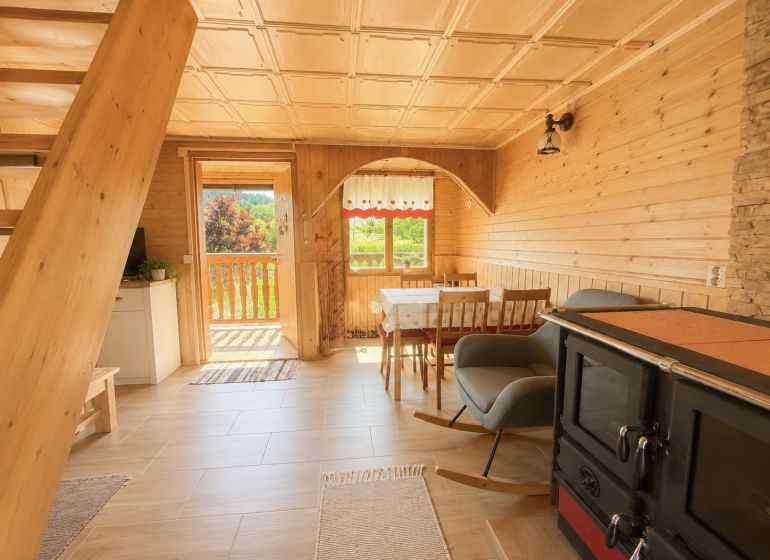 Wooden interior of a cabin with a kitchenette and a sofa, floor with wooden decor.