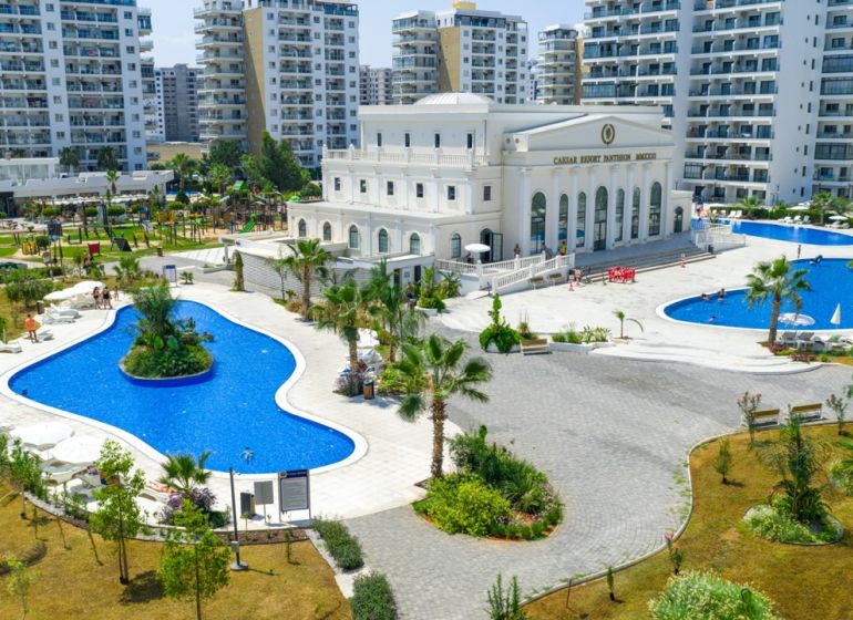 Exterior in Iskele with pools, landscaped gardens, and surrounding apartment complexes.