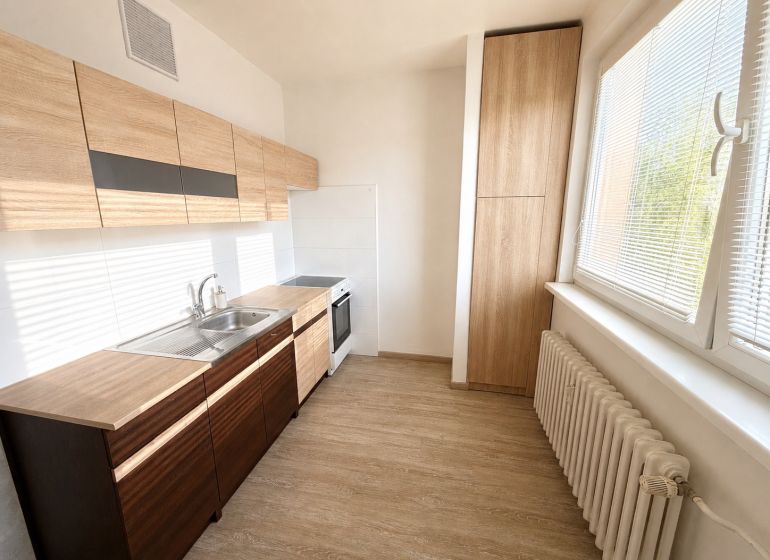 A kitchen in a 2-room apartment with wooden decor and large windows.