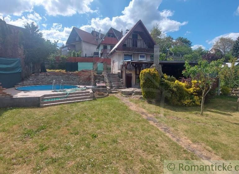 A cottage in Holíč with a pool and a garden surrounded by green vegetation.