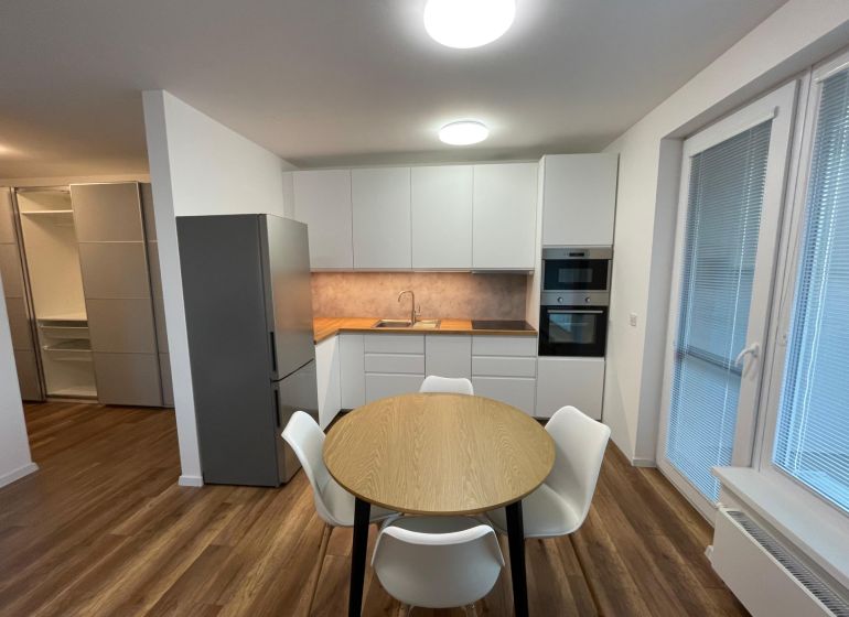 A kitchen in a 2-room apartment with a wood-patterned floor and built-in appliances.