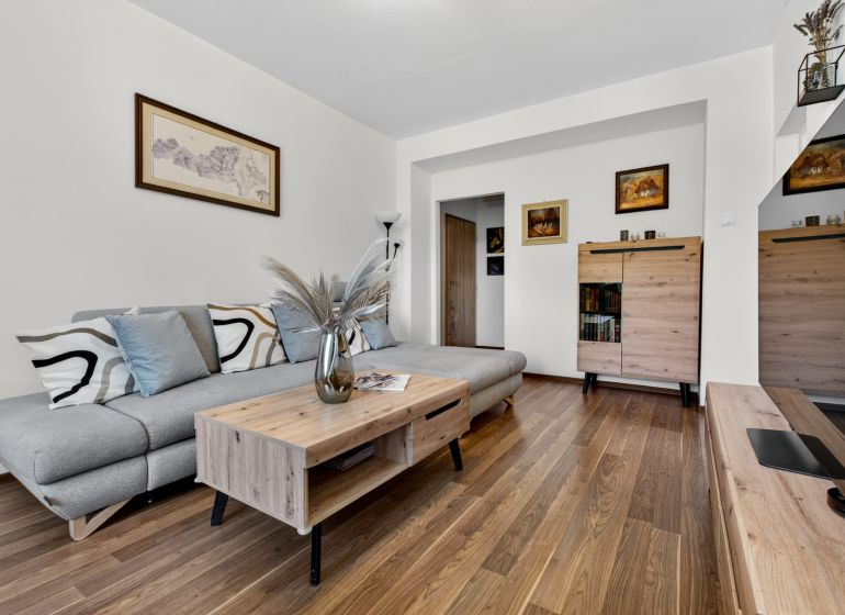 Living room in a 3-room apartment with a gray sofa and a floor with a wooden decor.