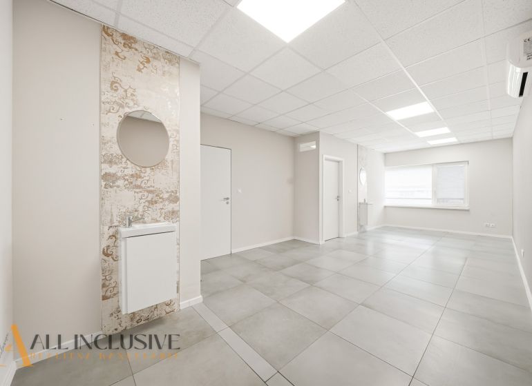 Commercial premises with ceramic flooring, light-colored walls, and a sink with a round mirror.