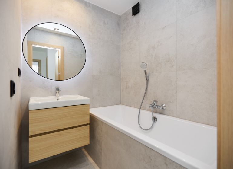 A bathroom with a bathtub and a sink in a 4-room apartment with wooden decor.