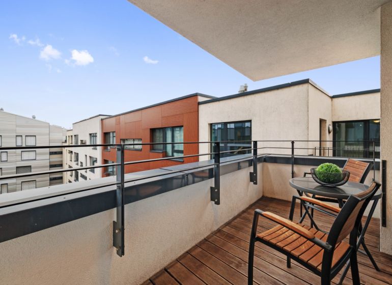 A balcony with wooden decor and furniture, view of the surrounding buildings.