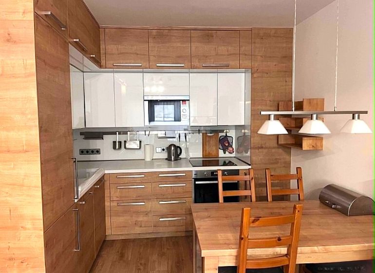A kitchen in a 2-room apartment with white cabinets and wooden decor.