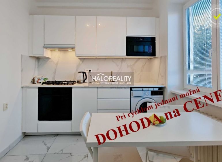 A kitchen in a 2-room apartment with white cabinets and marble tiles.