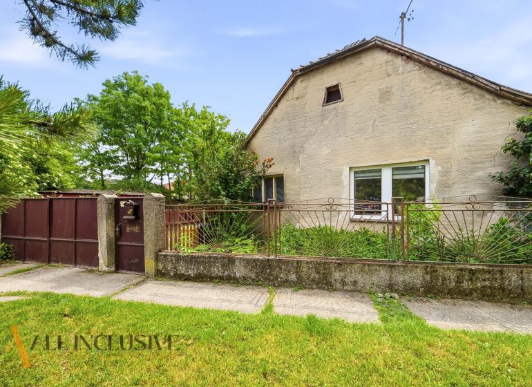 A family house in Lehnice with a gate, a fence, and trees in the yard.