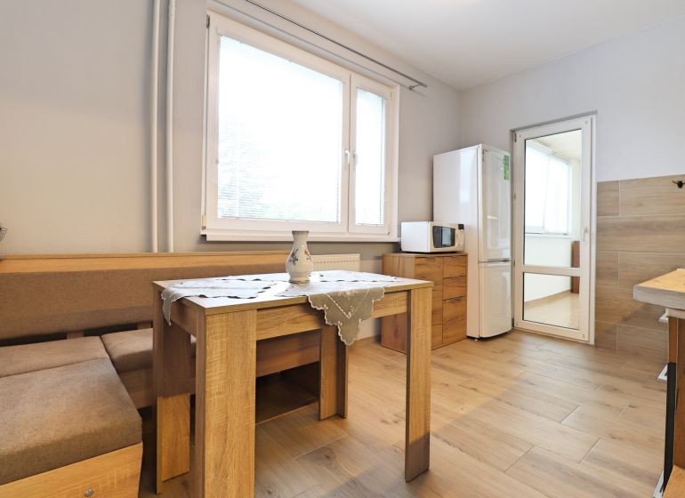 A kitchen in a 3-room apartment with a wooden decor floor and a dining table.