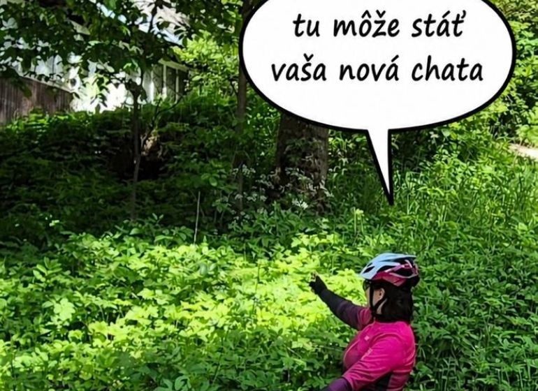 A cyclist in Terchová points to plots - housing surrounded by dense greenery.