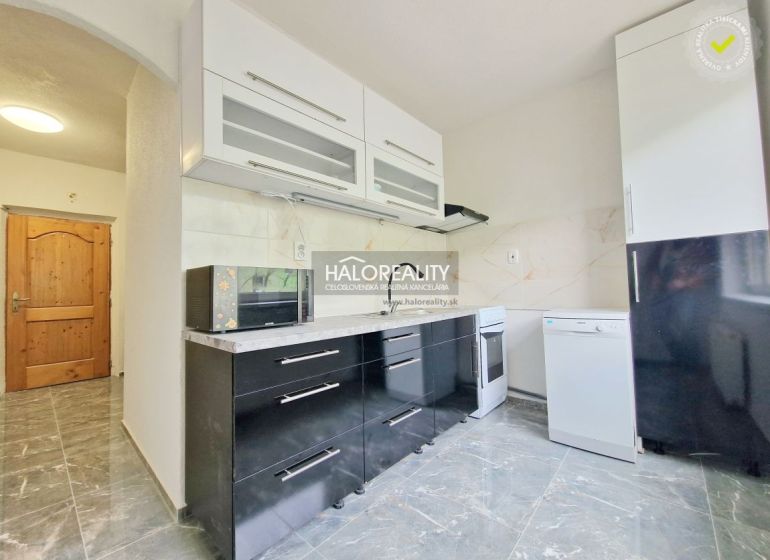 A kitchen in a 2-room apartment with black cabinets and appliances, and a floor with a wooden decor.