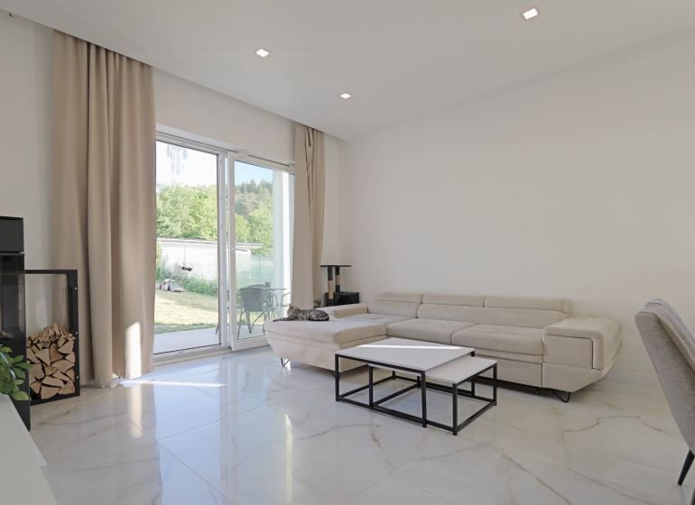 Living room in a family house with a fireplace, sofa, and large windows.