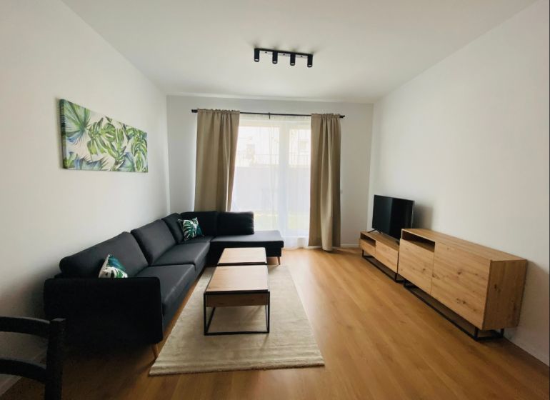 Living room in a two-room apartment with a wooden decor floor and a comfortable sofa.