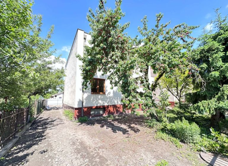 A family house in Dunajská Streda with trees and a landscaped garden in sunny weather.