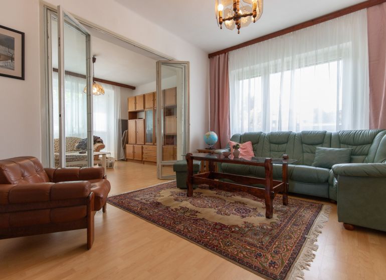 Living room in a 3-room apartment with a wooden decor floor and a folding wall.