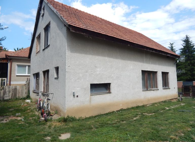 A family house in Strekov with a brick roof and two bicycles by the wall.