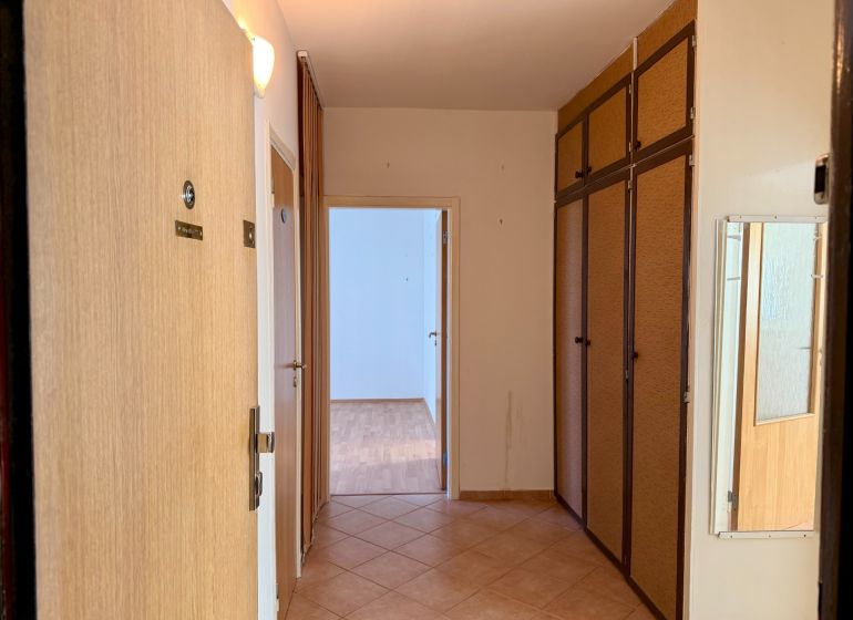 A hallway with a wardrobe and flooring in the decor of a 4-room apartment, light walls.