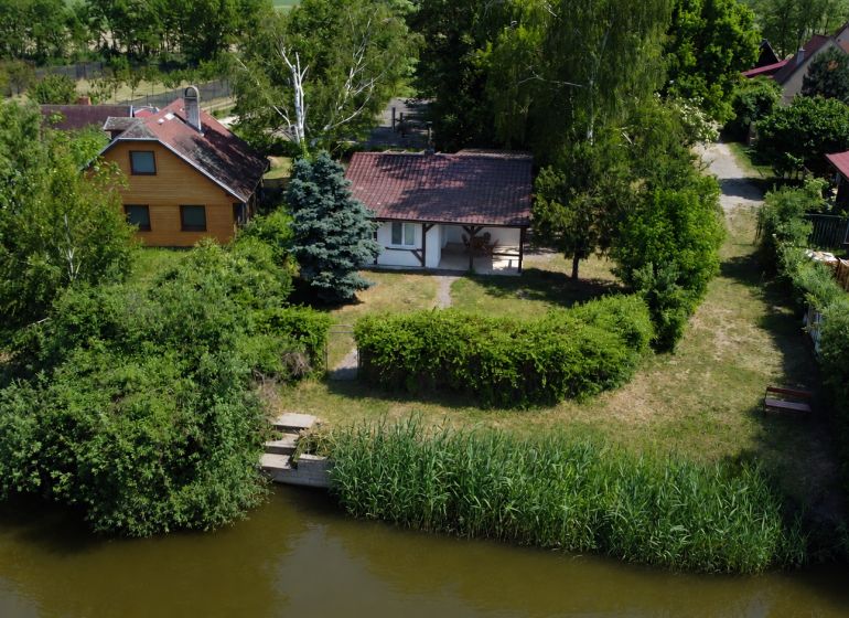 Green garden, a cottage by the water in Kopčany surrounded by greenery and trees.