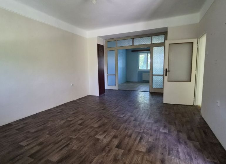 A room in a 3-room apartment with a floor featuring a wooden decor and white walls.