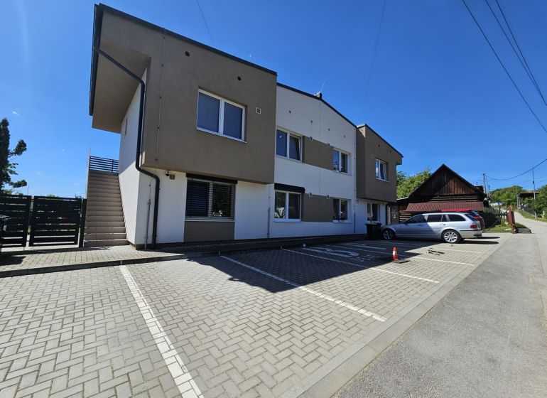 Apartment building in Štiavnik, Štiavnik with a parking lot and sunny sky suitable for a 1-bedroom apartment.