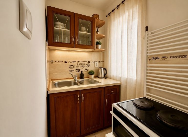 A kitchenette in a studio apartment with two cabinets, a curtain, and an electric stove.