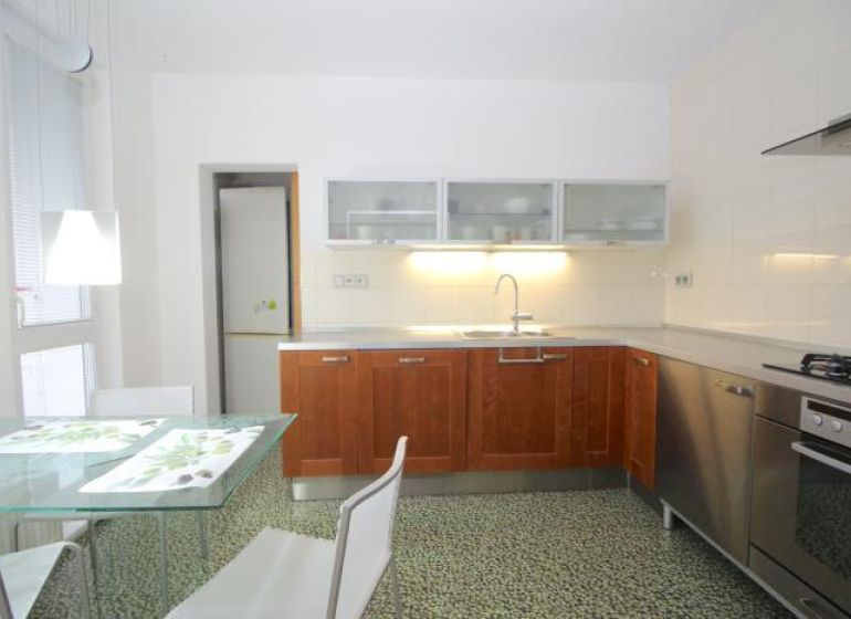 A kitchen in a 3-room apartment with a dining table and white chairs.