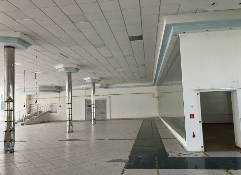 Commercial spaces with white tiles, columns, and stairs in the background.