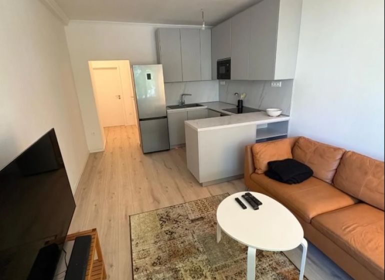 Living room with a sofa, TV, carpet, and kitchen in a 3-room apartment.