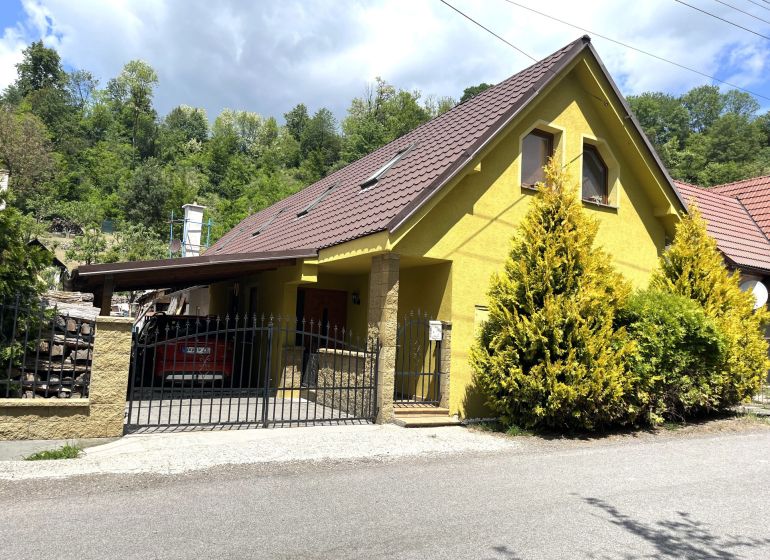 A family house in Bartošova Lehôtka with a yellow facade, a brown roof, and a front garden.