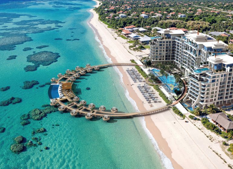 Beach resort by the turquoise sea with white sand and wooden villas in Paje.