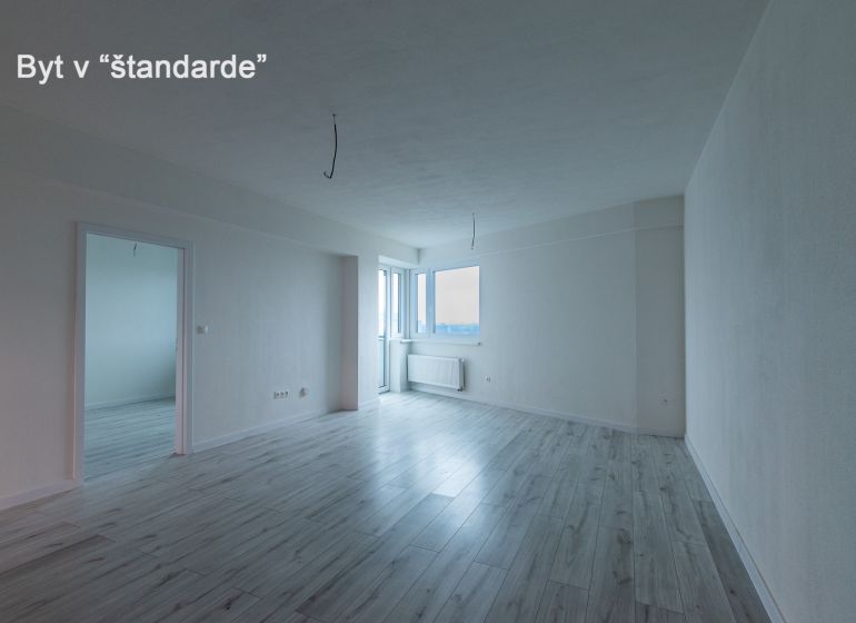 Spacious living room in a 2-room apartment with a wooden decor floor.