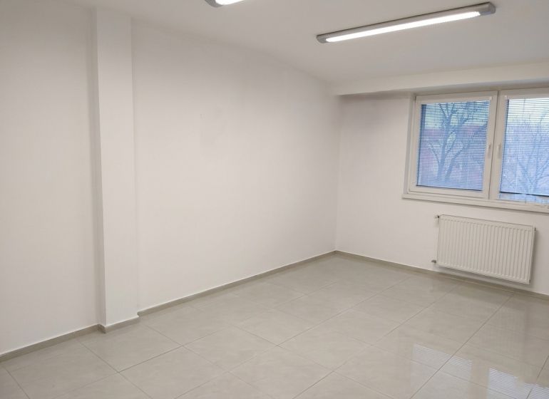 Bright room in an office with white walls, a window, and a tiled floor.