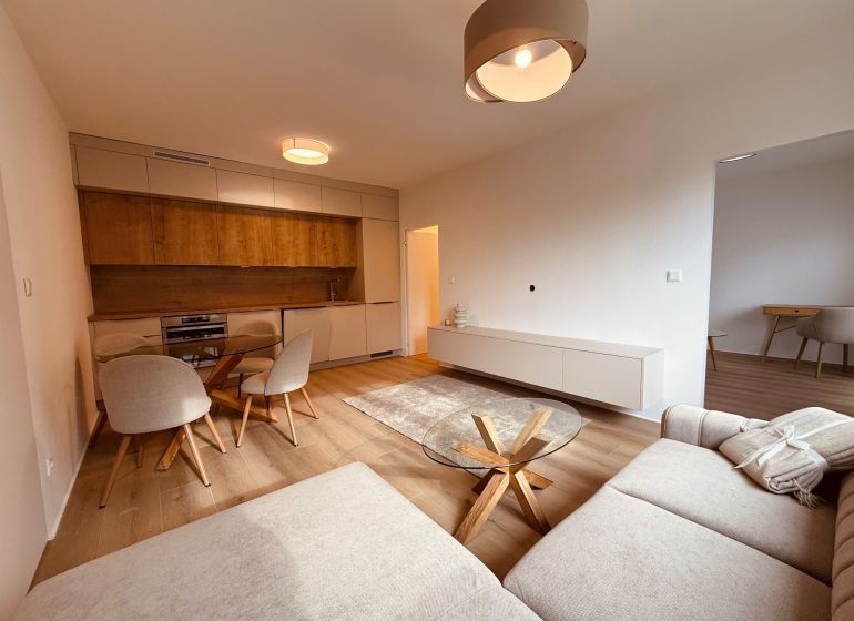 Living room with wood-patterned flooring and kitchen in a 3-room apartment.