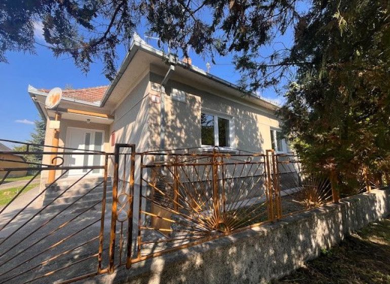A family house in Vrakúňa with a decorative metal fence and trees in the background.