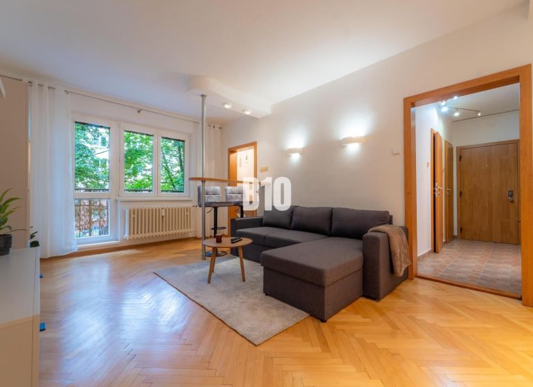 Living room in a two-room apartment with a wooden decor floor and a large window.