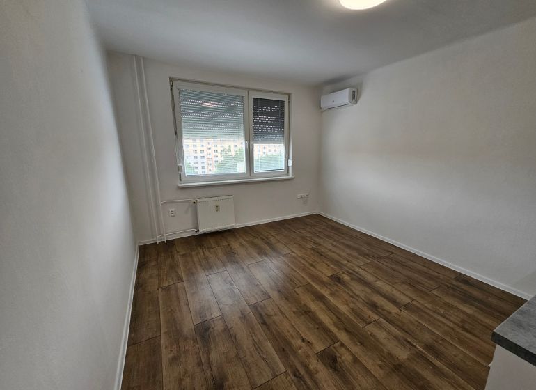 A studio apartment with air conditioning and a wooden decor floor offers a bright and cozy space.