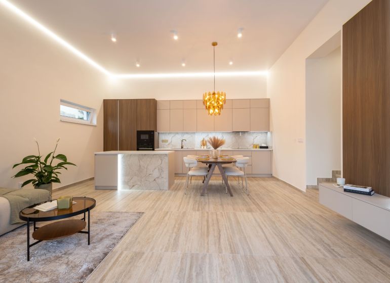 A kitchen and living room in a family house with a decorative light fixture and a wooden decor floor.