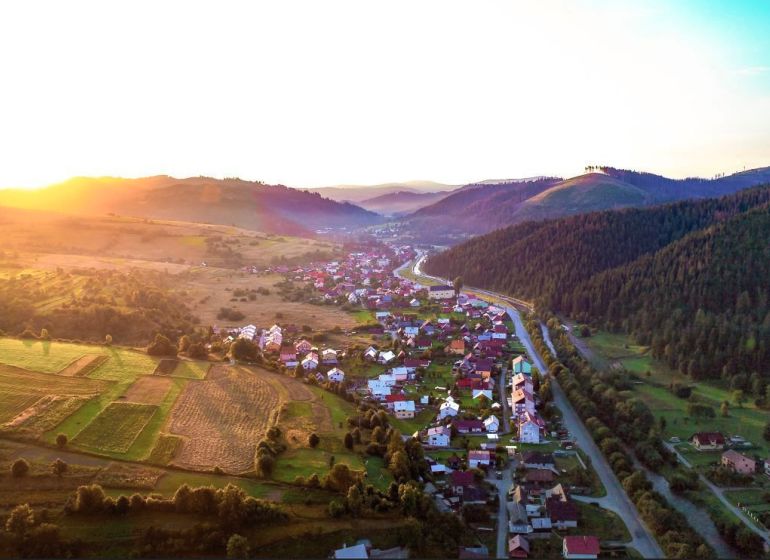 The landscape around Nová Bystrica with agricultural and forest lands at sunset.