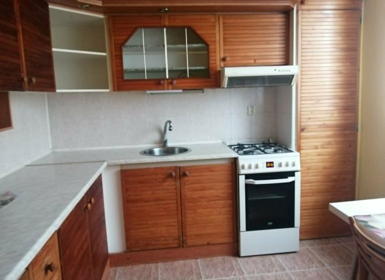 A kitchen in a 3-room apartment with a wooden decor kitchen unit.