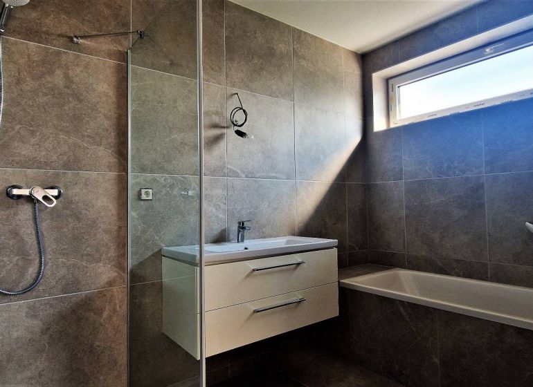 A bathroom with a shower and a bathtub in a 4-room apartment.
