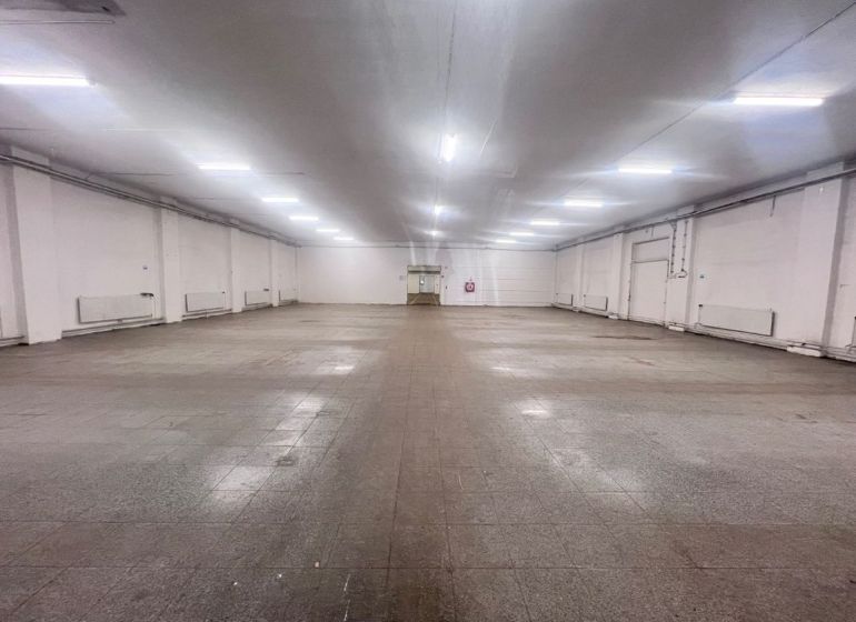 Spacious interior of warehouses and halls with ceiling lighting and tiled flooring.