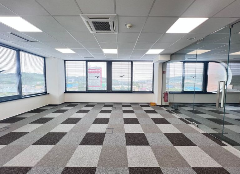 Spacious offices with carpeted floors, large windows, and glass walls.