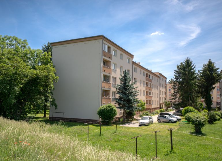 Apartment buildings on Švermova Street in Trenčín with surrounding greenery and parked cars.