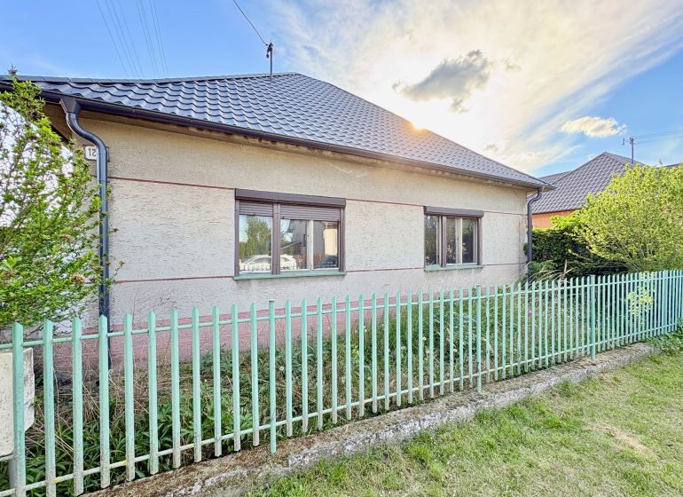 A family house in Šoporňa with two windows and a metal fence.