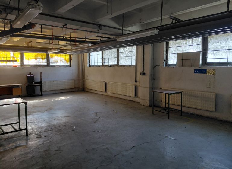 Warehouse space with concrete floor, windows, and old furniture. Warehouses and halls.