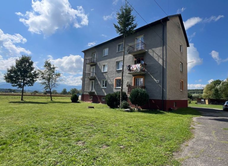 An apartment building in Pribylina surrounded by greenery and blue skies, with a view of the surrounding landscape.