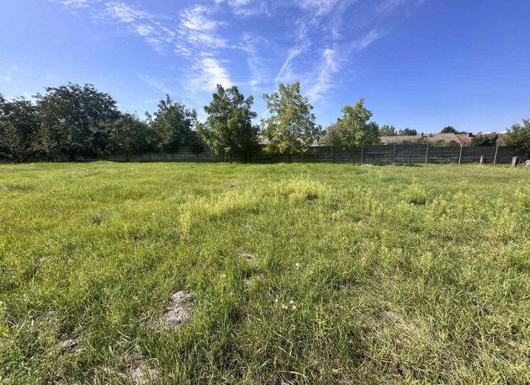 Peaceful greenery designated for residential plots in Vydrany, surrounded by trees and a fence.